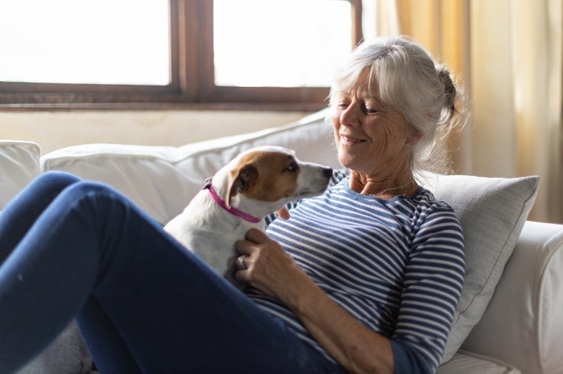 TYMLOS patient sitting on the couch with the dog nestled in her lap. Not actual patient